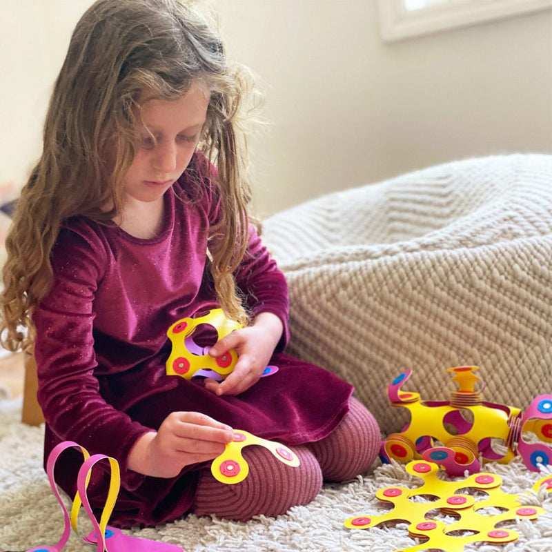a girl building with her magnetic pieces from clixo