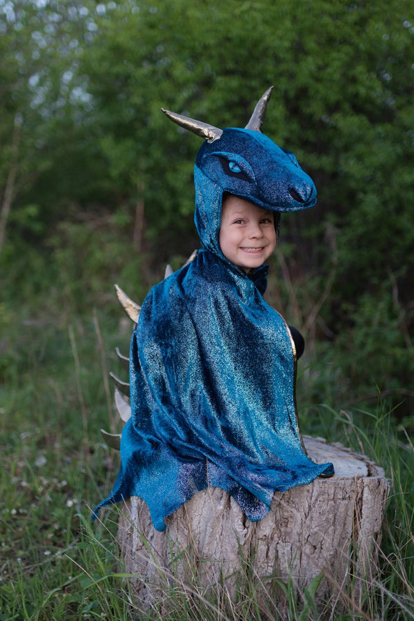a boy sits on a log in his great pretenders blue and gold dragon costume 