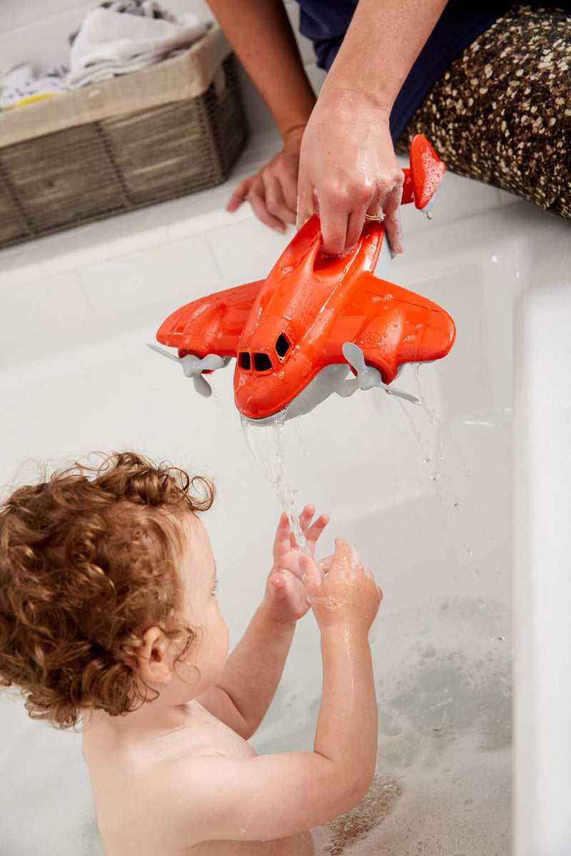a baby plays with the green toys fire plane in the bath