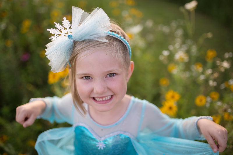 a girl smiles wearing the great pretenders ice queen costume for kids