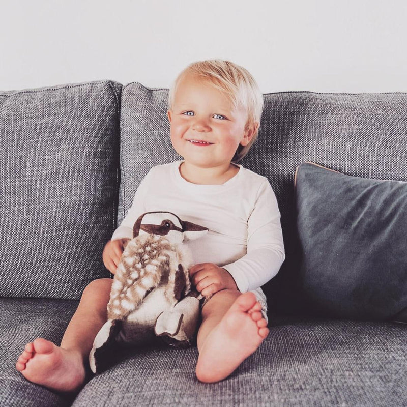 a baby sits with his nana hutchy soft toy kookaburra in brown and white