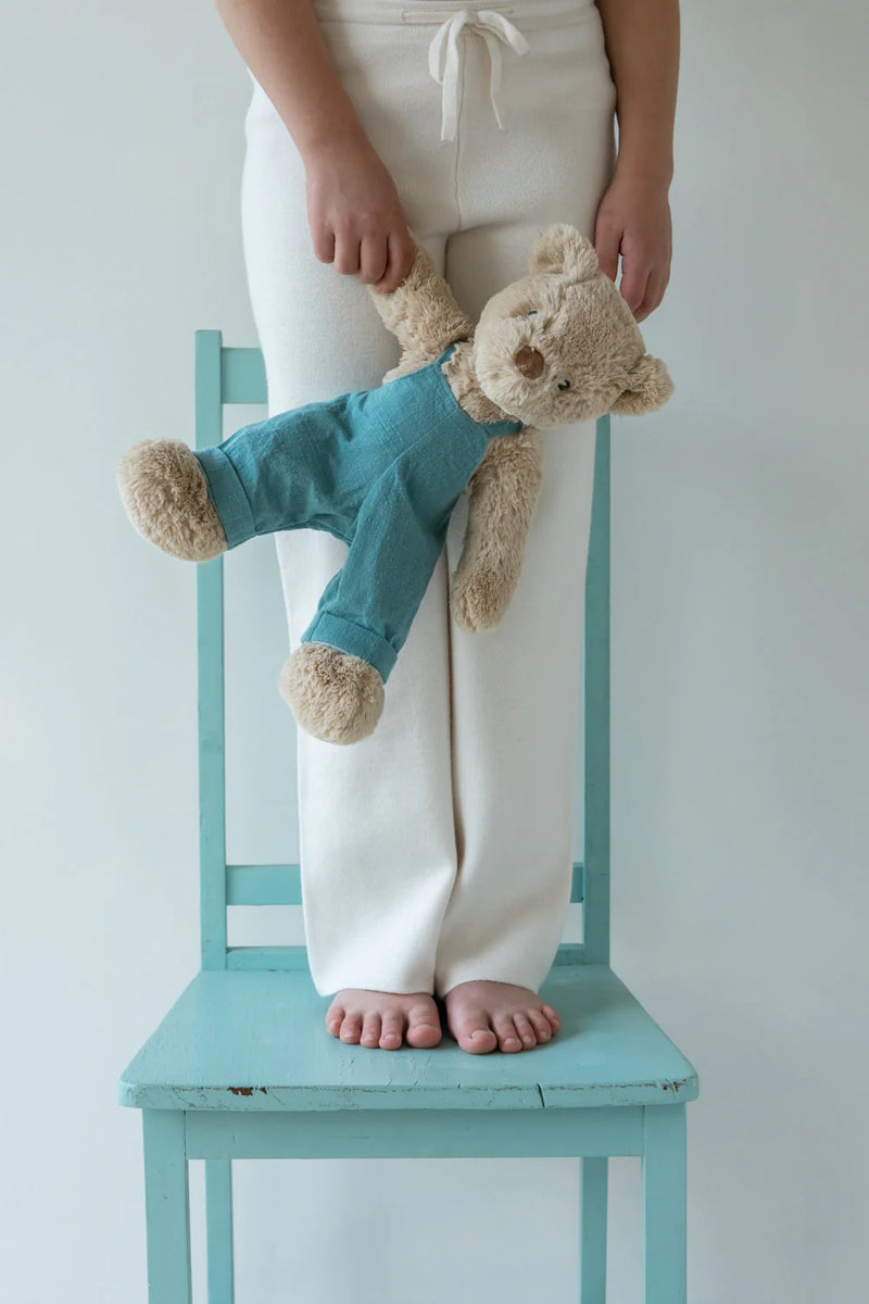 a girl holding her nana huchy honey bear with blue overalls on