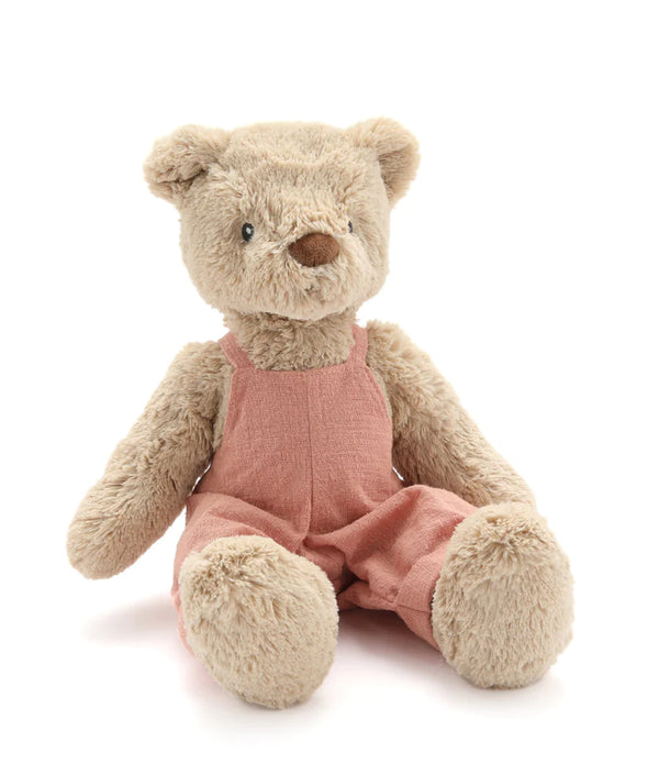 a beige soft bear toy in a pink linen overall outfit