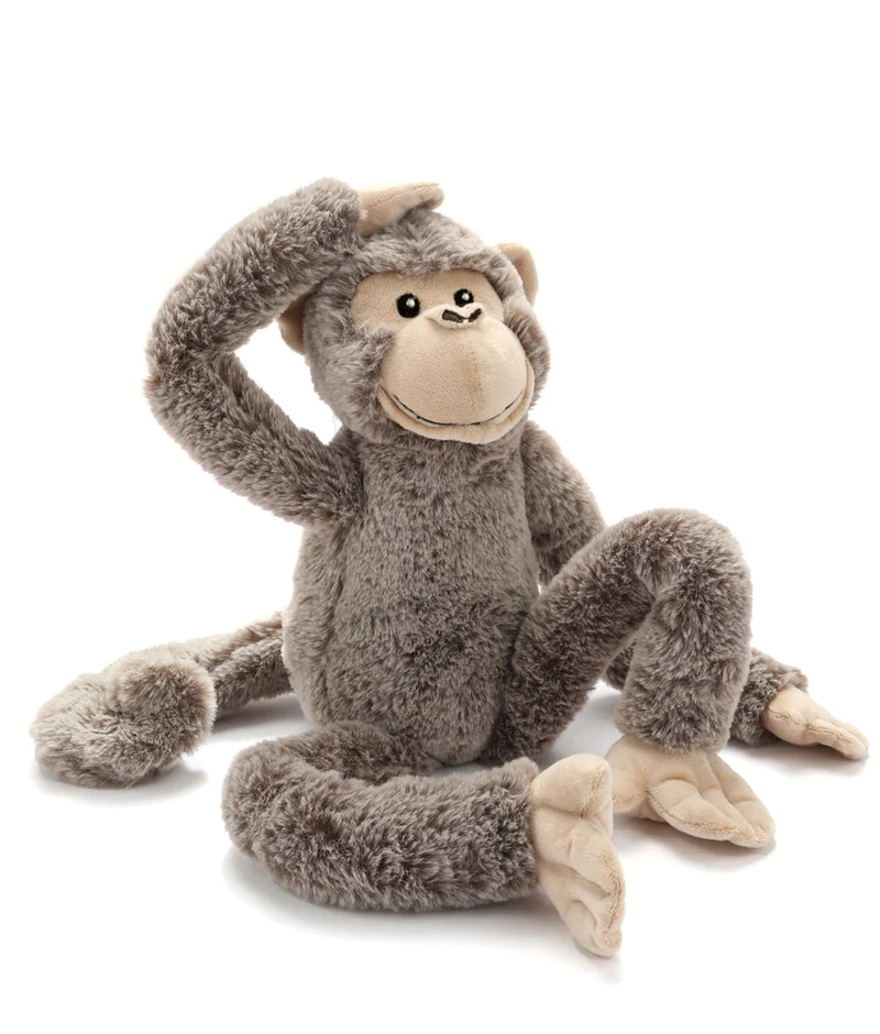 soft toy monkey sitting on the ground with one hand on his head