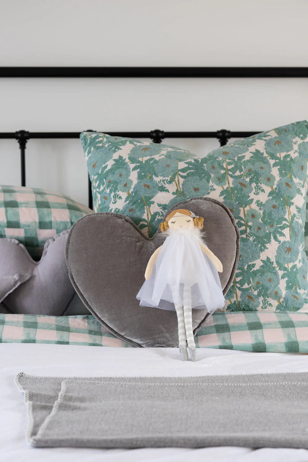 a doll on the bed with white tulle outfit and buns in her hair and a silver star headband