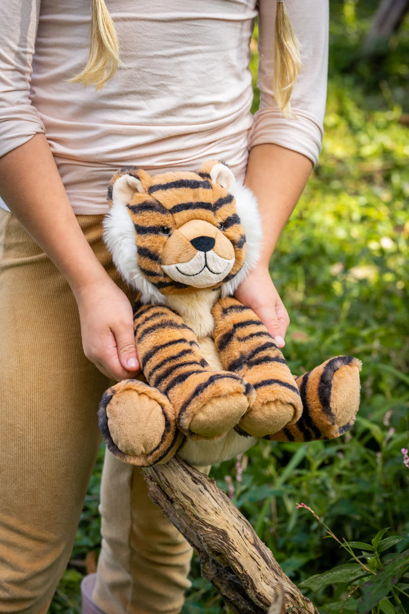 a girl holding her tiger soft toy outside 