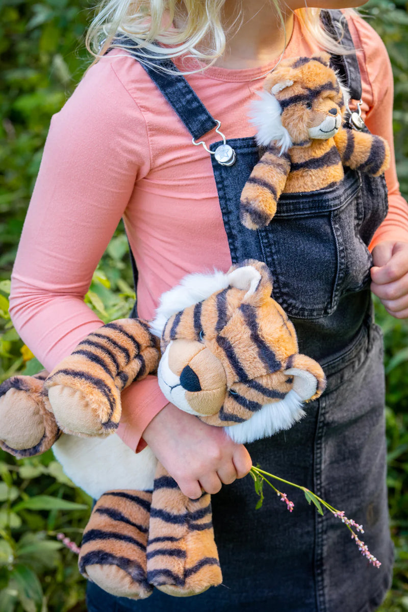 a girl holds her tiger soft toy under her arm and another smaller one in her pinafore pocket