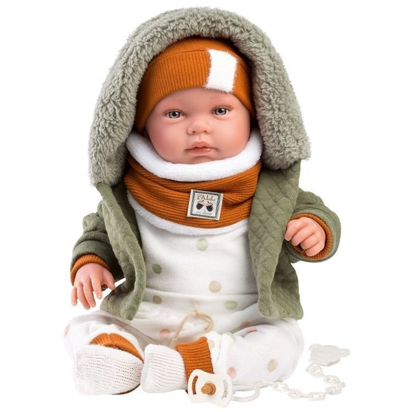 Baby doll wearing a green coat, orange hat, and scarf on a white background