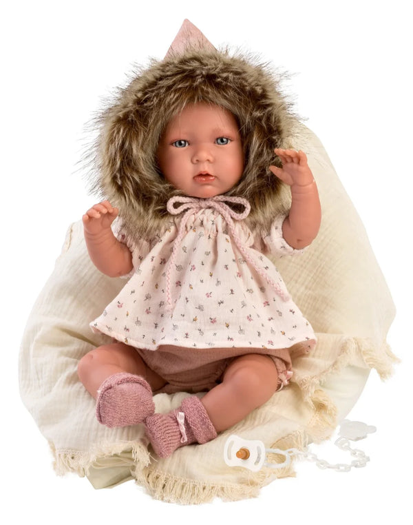 Baby doll in a pink outfit with a fur hood on a white background
