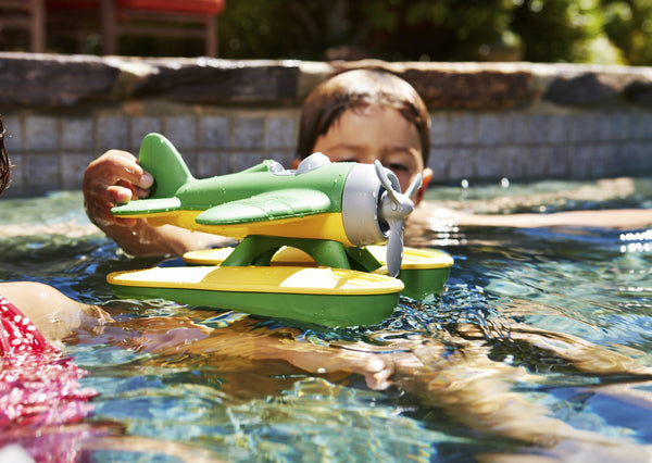 a child in the pool with his green and yellow seaplane floating