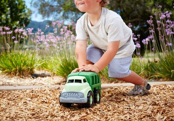 the green toys recycling truck being pushed by a kid in the park