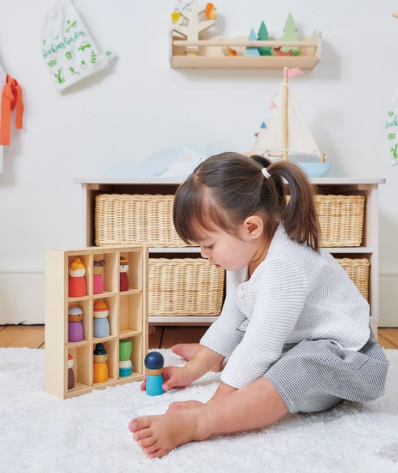 a child plays with her wooden toy hotel in a play room