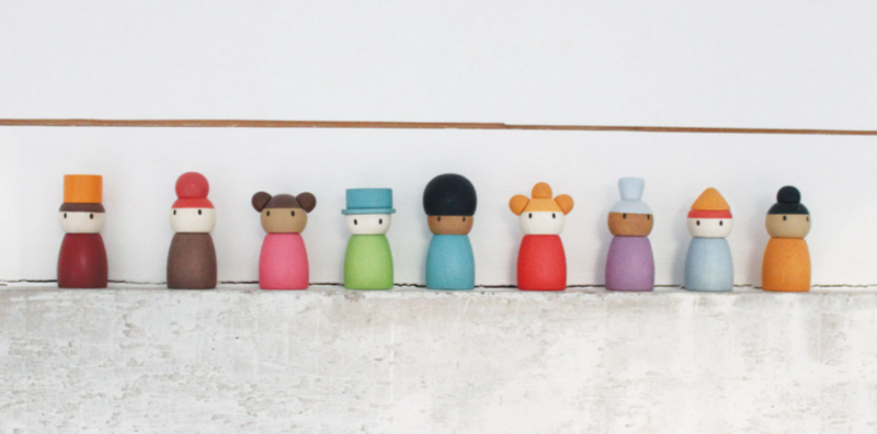 9 wooden toy characters in a row against a wall
