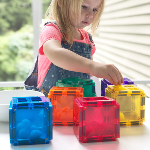 a child creates rainbow coloured boxes out of her connetix large tiles set