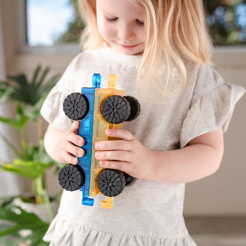 a child plays with the connetixs cars holding them back to back 