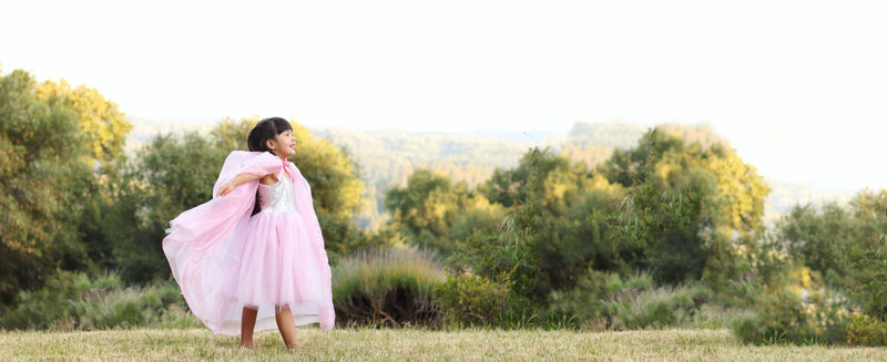 a girl wears the pink sequin girls dress with a tulle cape 