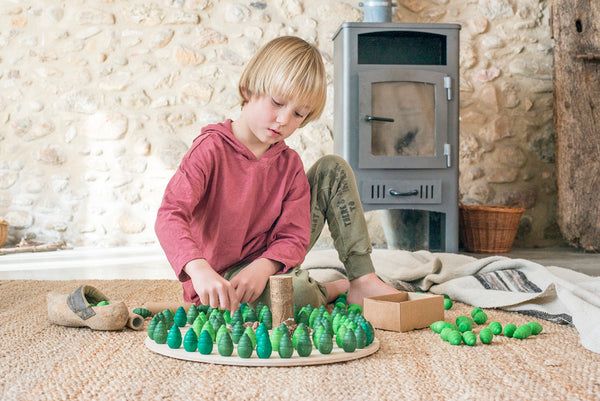 a child places the grapat wooden tree mandalas round a wooden board