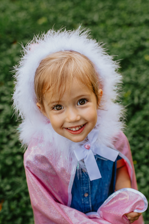 a girl wears a cape costume with a white fully collar and pink glitter fabric