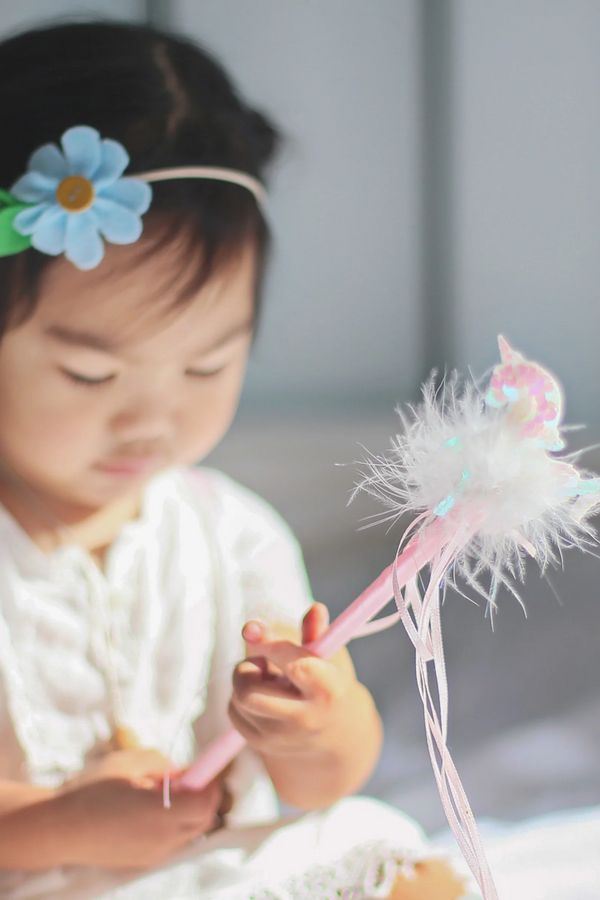 a girl plays with a pink unicorn wand with sequin details