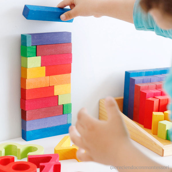 a child stacks the grimms rainbow stepped pyramid blocks up