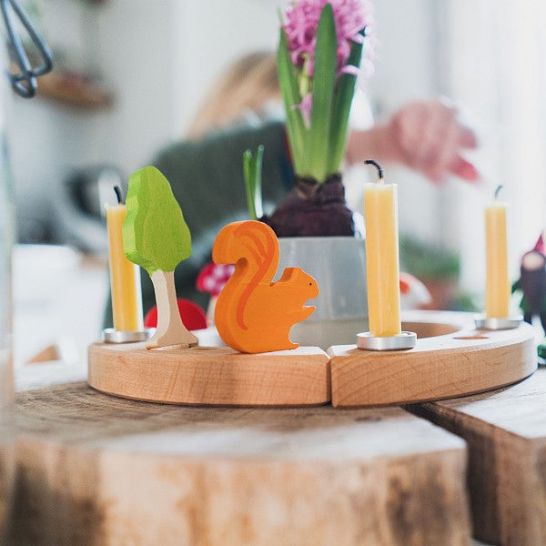 grimms small birthday ring in natural wood on a wooden table with a flower vase placed in the middle and decorated with candles and wooden animal figures