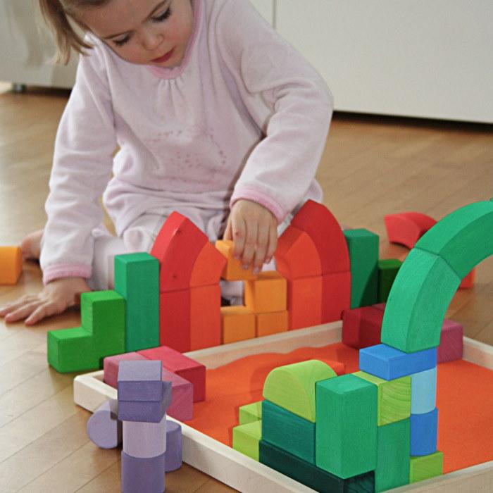 a child builds bridges and structures with her grimms romanesque building block set