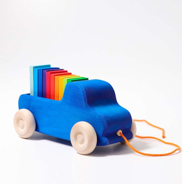 the grimms wooden pull along car in blue with rainbow dominos in the back