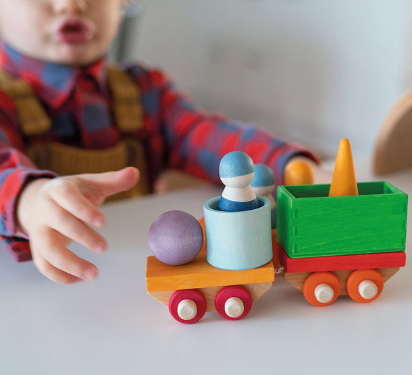 a child plays with the wooden train set from grimms