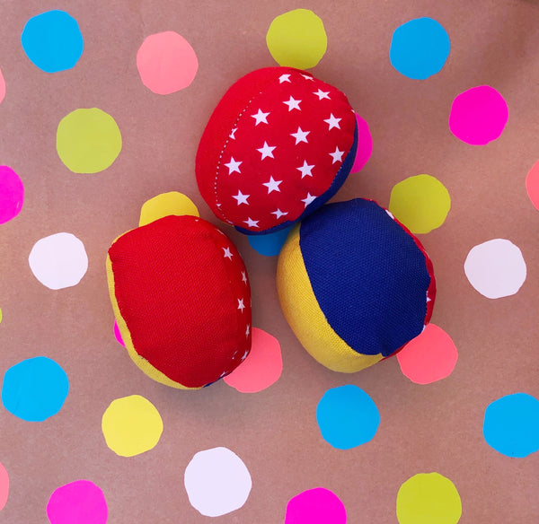 a set of three juggling balls in red and blue and yellow with some white star prints