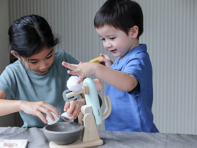 two children play with their pretend kitchen mixer set from plan toys
