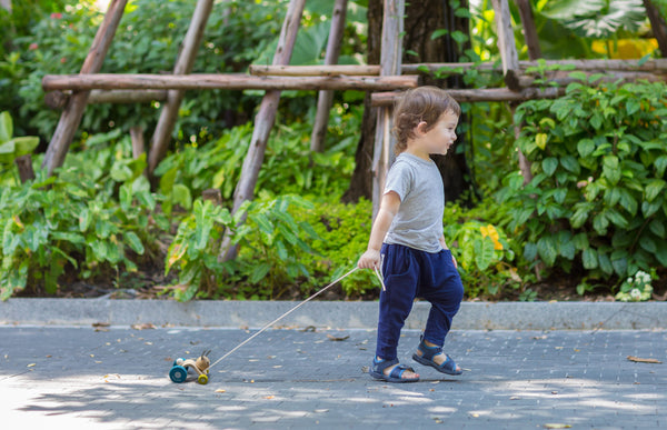 a toddler pulls the plan toys wooden hopping rabbit along
