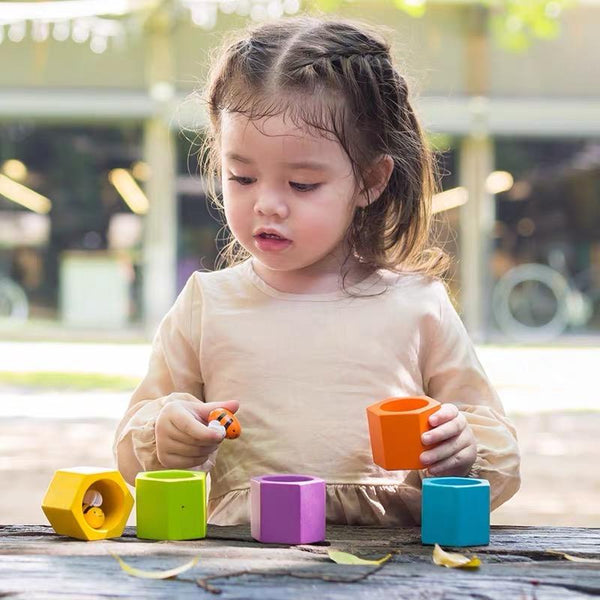 a girl plays with the plan toys wooden beehive set 