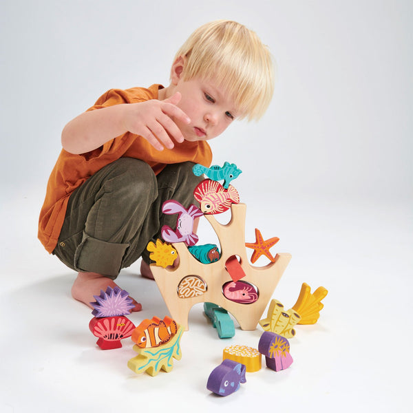 a child plays with the tender leaf wooden stacking coral reef toy